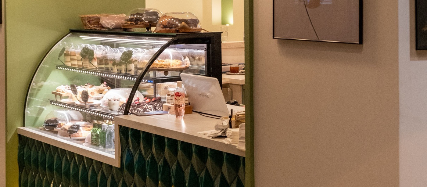 Balcão de cafeteria com vitrine refrigerada e azulejo verde